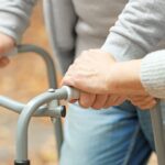Transitional Care Caregiver helping patient with a walker