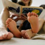 pexels-kseniachernaya-7295900 adult and children's feet shown while both people are reading a book